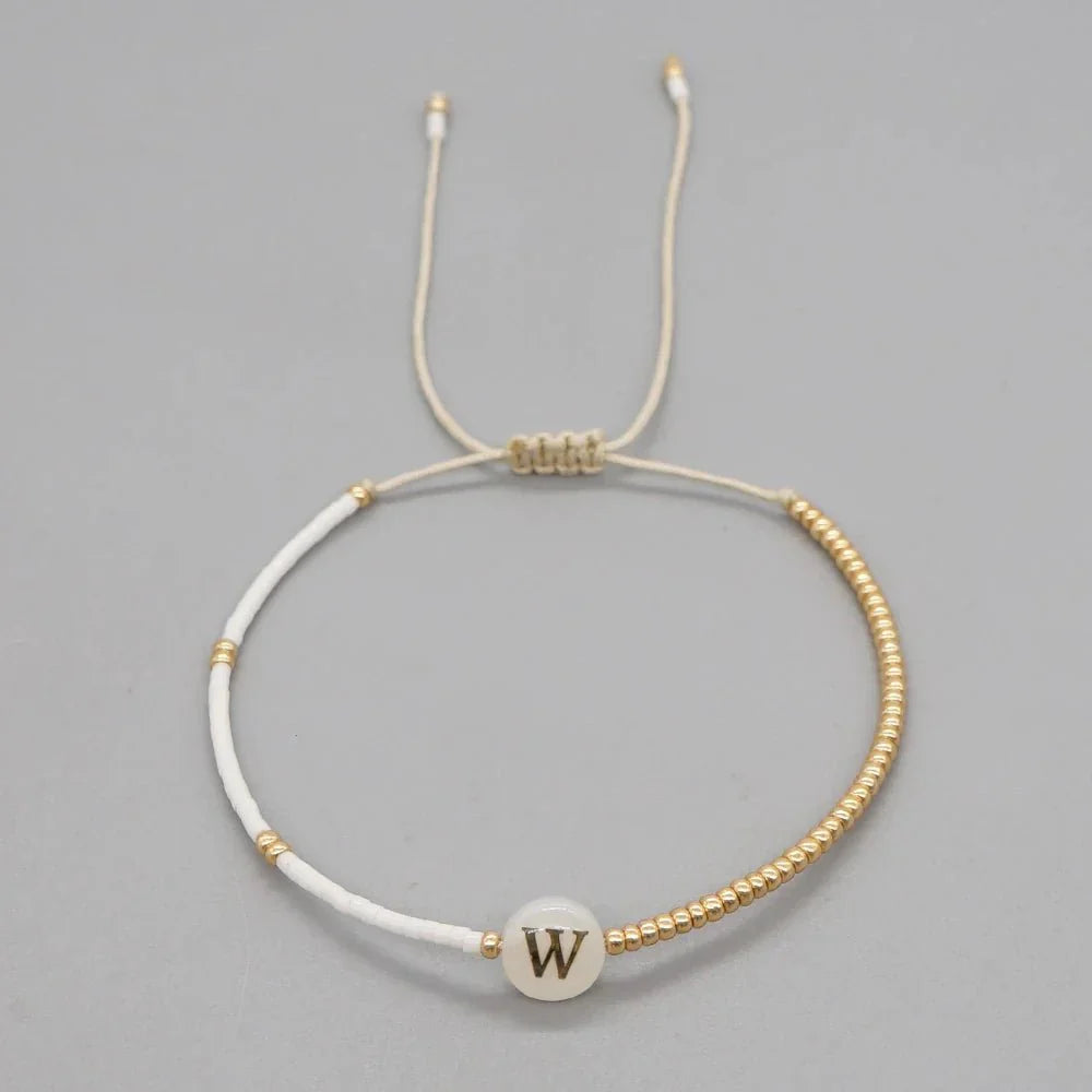 Bracciale boho con perline bianche e oro e iniziale personalizzabile
