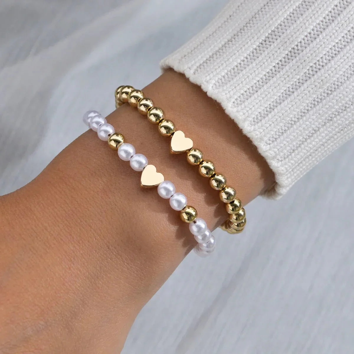 Set 2 bracciali con perline bianche e oro e ciondolo cuore