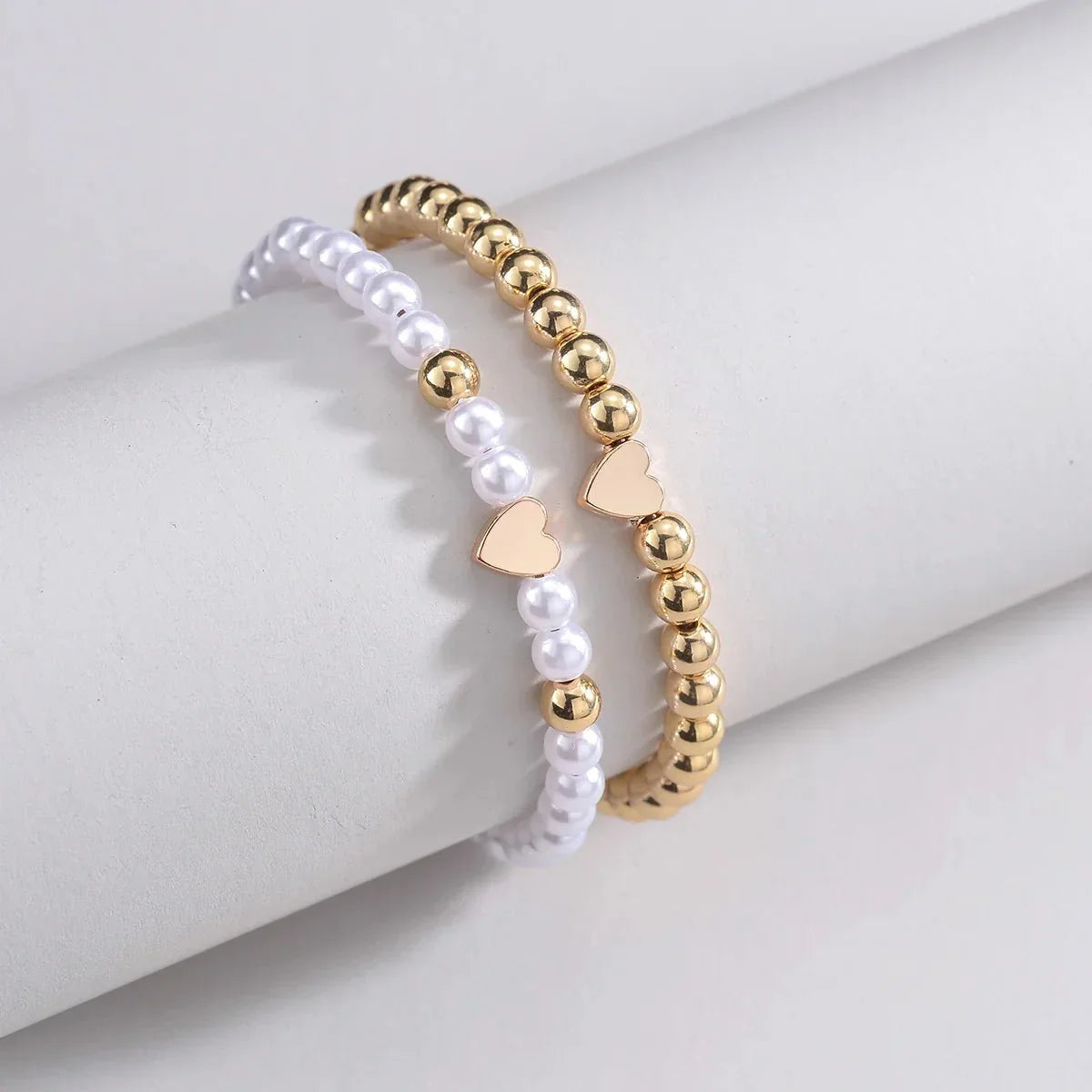 Set 2 bracciali con perline bianche e oro e ciondolo cuore