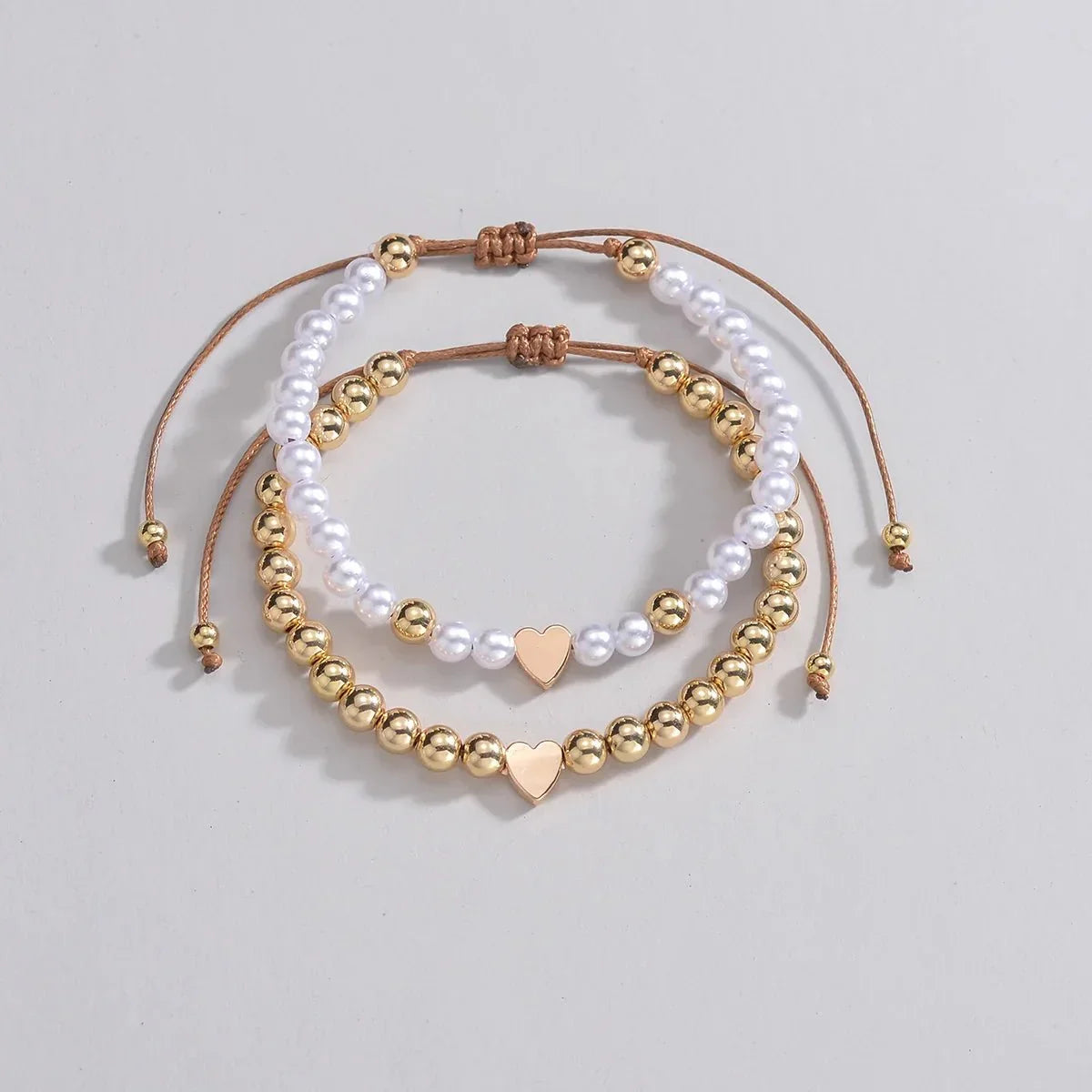 Set 2 bracciali con perline bianche e oro e ciondolo cuore